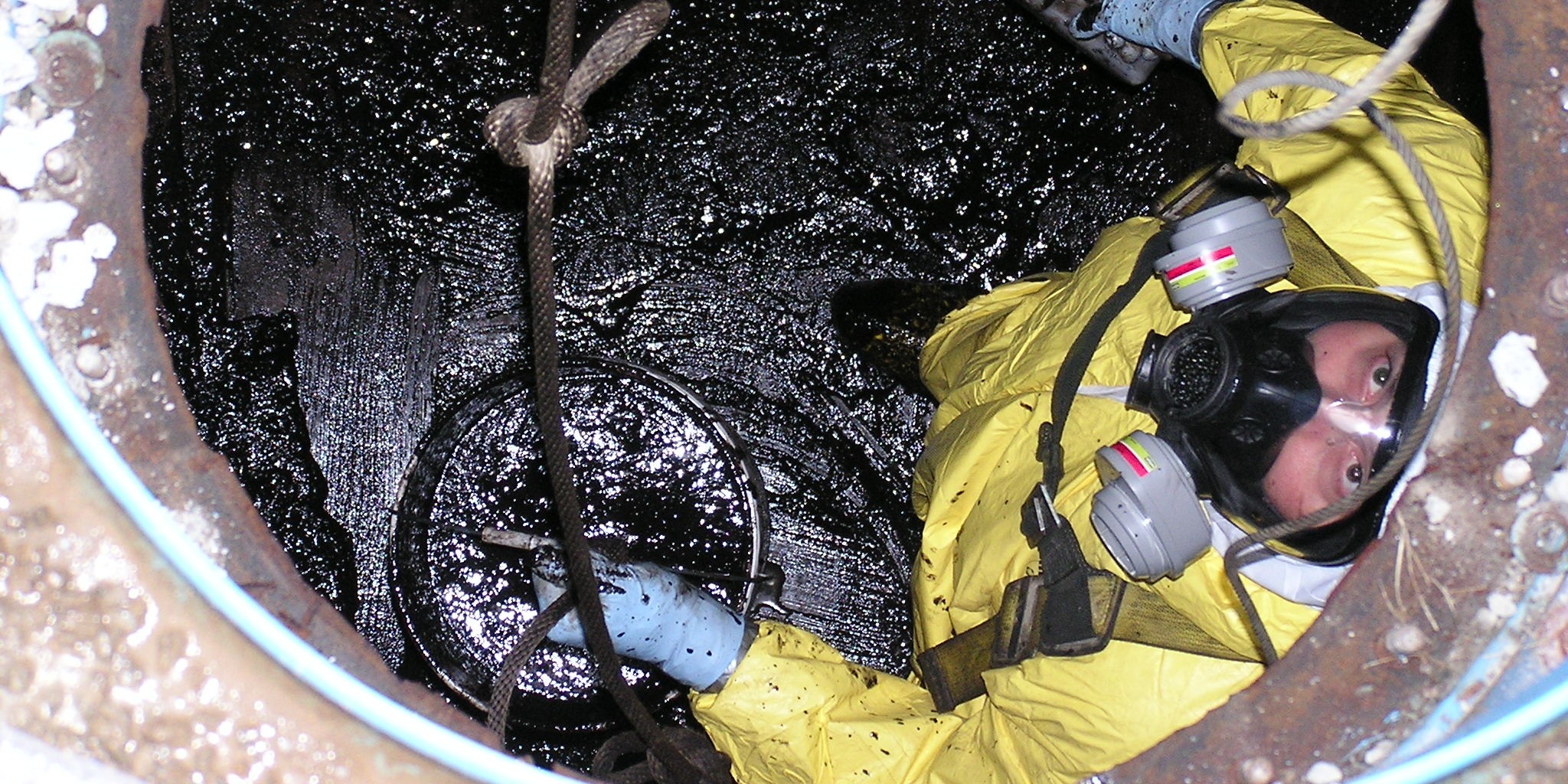 Closeup of a NEDT staffer performing confined space entry in a storage tank.